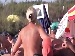 French naturist woman strokes cocks of two men on nudist beach